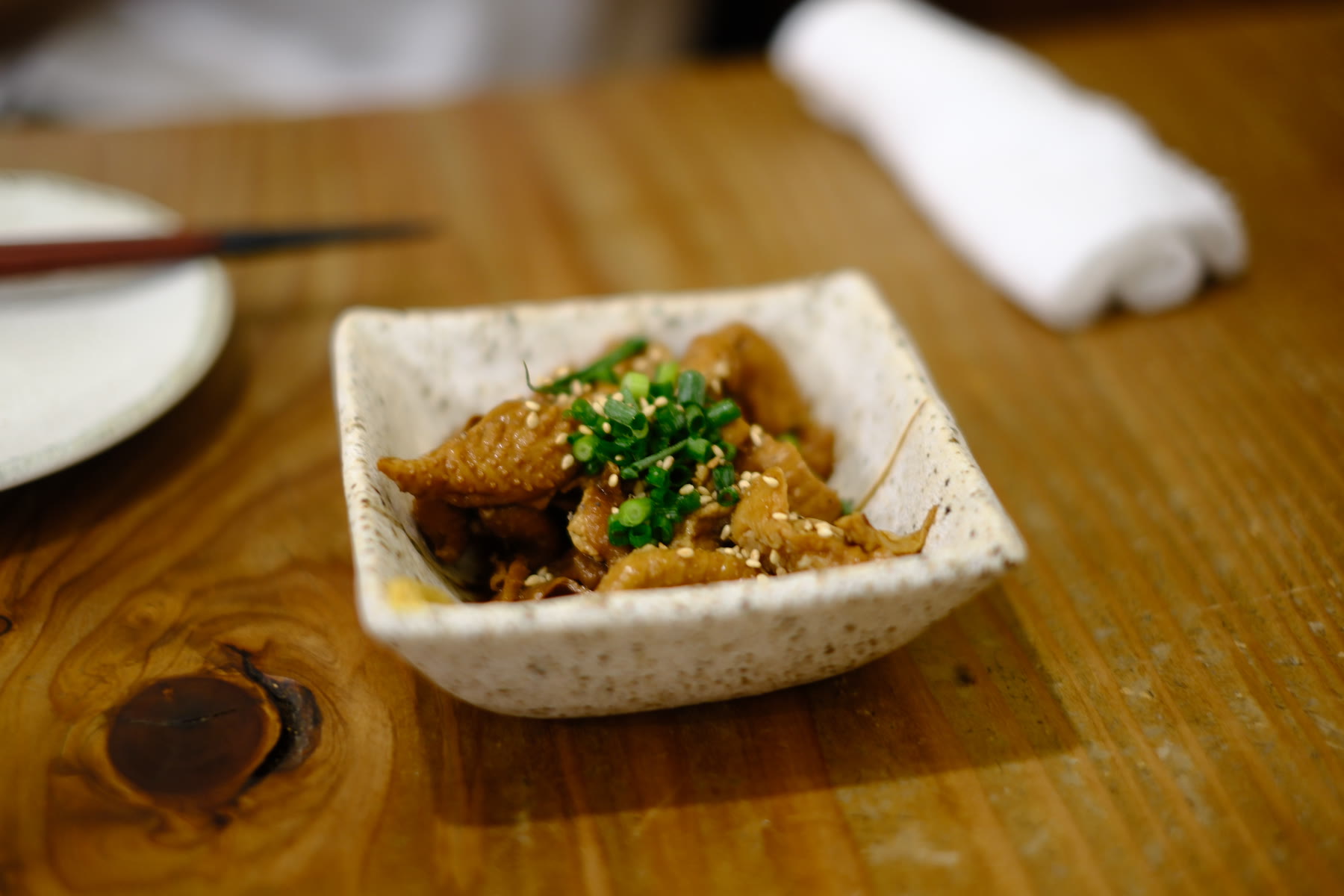 A small plated dish with green garnish on a wooden counter, photographed with a Fujifilm X-H2