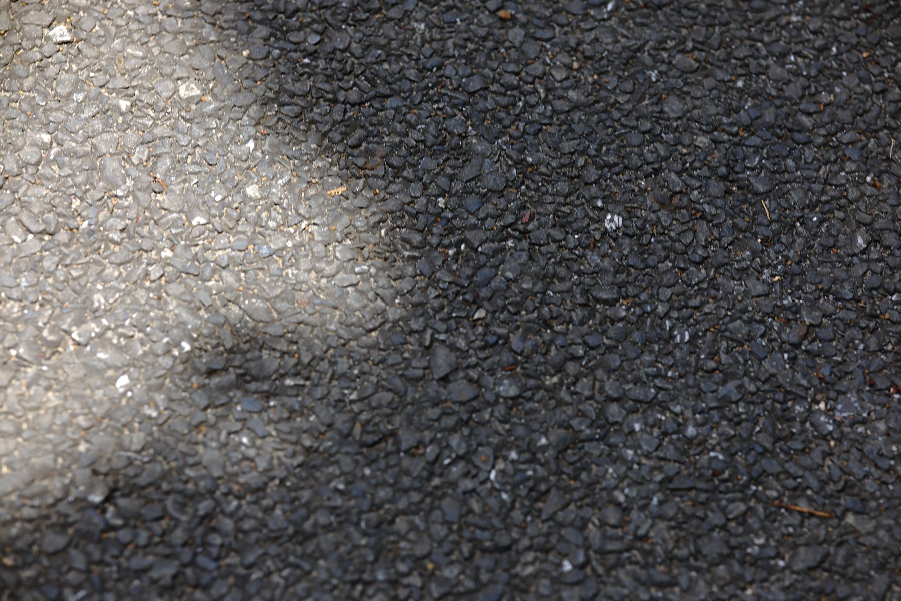 A used Tokyo pavement surface marked by light, texture, and time